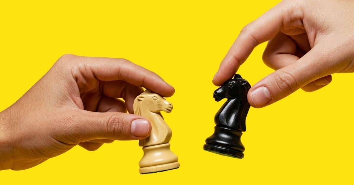Two hands facing each other holding a knight chess piece